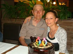 Älterer Herr feiert seinen 90. Geburtstag mit einer Torte gemeinsam mit einer jungen Frau